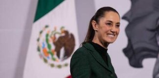 A woman in a green suit smiling in front of the Mexican flag