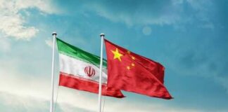Flags of Iran and China waving against a blue sky