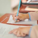 Poorest State DESTROYS Wealthiest in Stunning Reversal A student's hand holding a pencil while writing on a sheet of paper