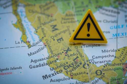 shutterstock_2690858521.jpg A yellow warning sign placed on a map of Mexico
