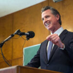 Newsom’s Shocking Israel Remarks: A Game-Changer? Man speaking at podium with microphones indoor setting