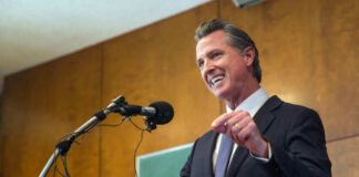 Man speaking at podium with microphones indoor setting