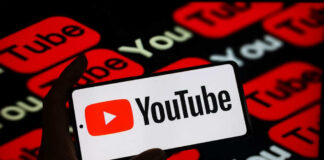 Hand holding phone showing YouTube logo.