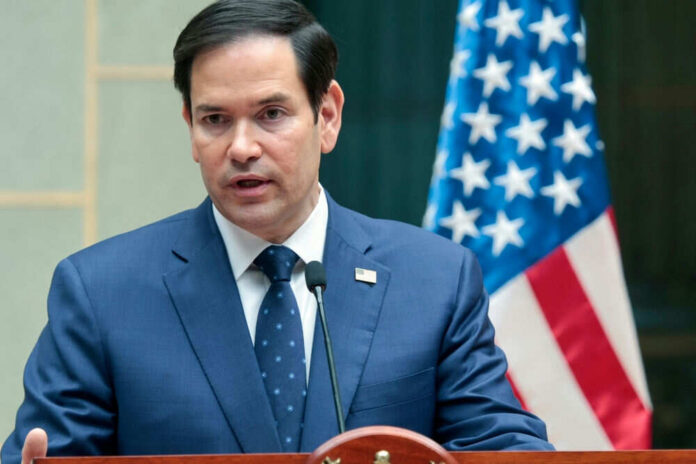 Man in suit speaking at podium with flag behind