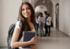 Smiling student holding books in a school hallway