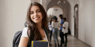 Smiling student holding books in a school hallway
