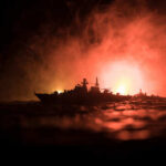 Silhouetted model ships against a smoky, illuminated background