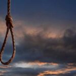 A noose hanging against a dramatic sky at sunset