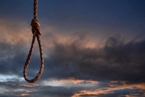 A noose hanging against a dramatic sky at sunset