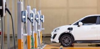 A white electric vehicle parked at a charging station with multiple chargers