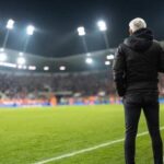 Death Stuns Football World Soccer coach observing the game from the sidelines at night