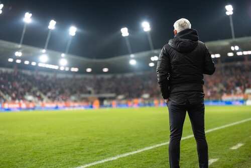 Soccer coach observing the game from the sidelines at night