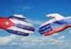 Hands painted with the Cuban and Russian flags reaching towards each other