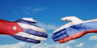 Hands painted with the Cuban and Russian flags reaching towards each other