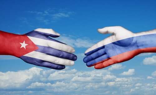 Hands painted with the Cuban and Russian flags reaching towards each other