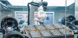Robotic arm assembling an electric vehicle battery in a display