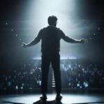 Silhouette of a speaker on stage with an audience in the background