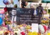 A memorial display with flowers, balloons, and a large photograph of a man with a message of remembrance