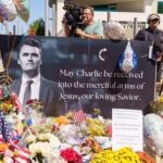 A memorial display with flowers, balloons, and a large photograph of a man with a message of remembrance