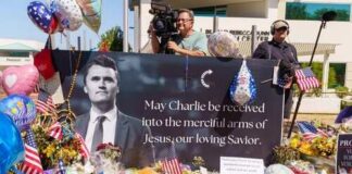 A memorial display with flowers, balloons, and a large photograph of a man with a message of remembrance
