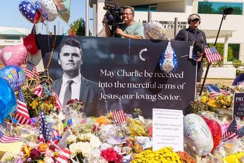 A memorial display with flowers, balloons, and a large photograph of a man with a message of remembrance