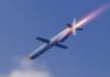 A missile in flight with a trail of smoke and flames