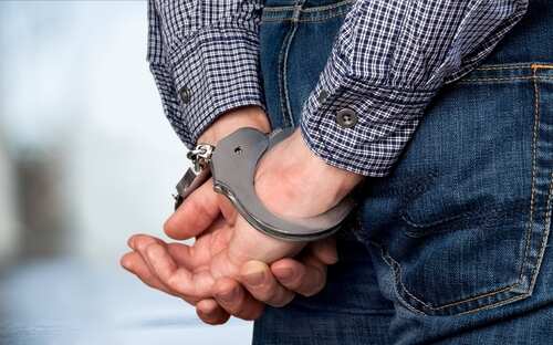 Person with hands handcuffed behind their back