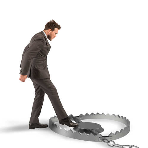 A man in a suit stepping towards a large bear trap