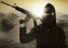 A masked individual holding a rifle in a military landscape