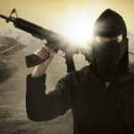 A masked individual holding a rifle in a military landscape