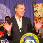 Man speaking at podium surrounded by smiling people.