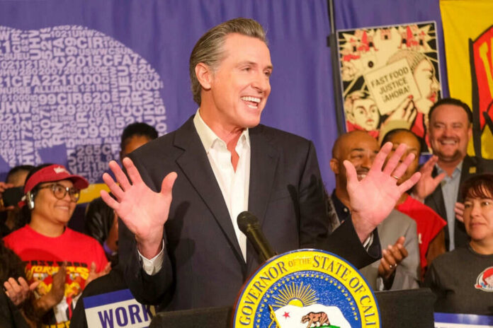 Man speaking at podium surrounded by smiling people.