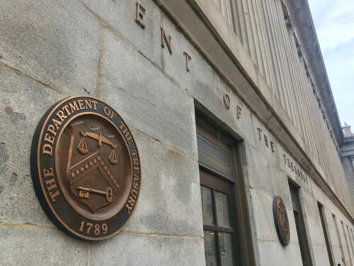 shutterstock_1274705839.jpg Exterior view of the Department of the Treasury building with a bronze plaque