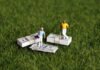 Golf’s Wealth Gap: Shocking Payout Inequality Two miniature golfers standing on stacks of money on grass