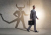 Businessman walking with a briefcase, shadow depicting a devil figure