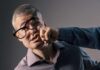 A man with glasses appears to be punched in the face by another person's fist