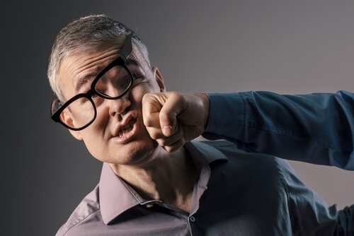 A man with glasses appears to be punched in the face by another person's fist