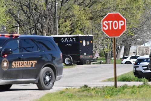 A sheriff's vehicle and a SWAT truck near a stop sign on a road