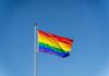 Rainbow flag waving against a clear blue sky