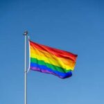 Rainbow flag waving against a clear blue sky