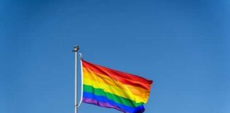 Rainbow flag waving against a clear blue sky