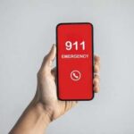 Hand holding a smartphone displaying an emergency call screen