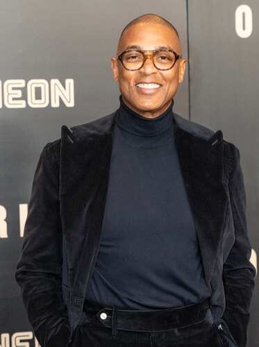 A smiling man in formal attire poses at a red carpet event