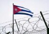 Cuban flag waving above a barbed wire fence