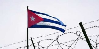 Cuban flag waving above a barbed wire fence