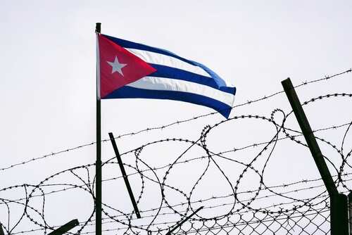 Cuban flag waving above a barbed wire fence