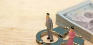 Miniature figures of a man and woman standing on handcuffs next to a stack of money