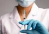 A healthcare worker holding a syringe with a blue needle
