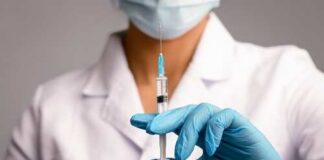 A healthcare worker holding a syringe with a blue needle