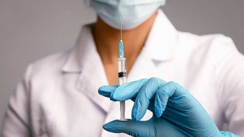 A healthcare worker holding a syringe with a blue needle